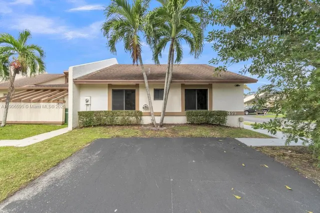 a view of a house with a yard and palm trees