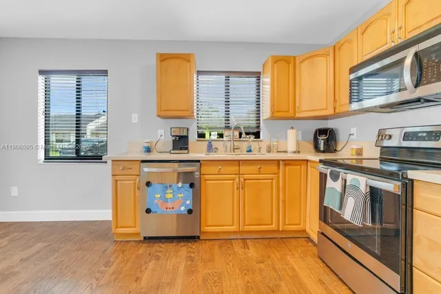 a kitchen with stainless steel appliances a sink a stove a refrigerator and cabinets
