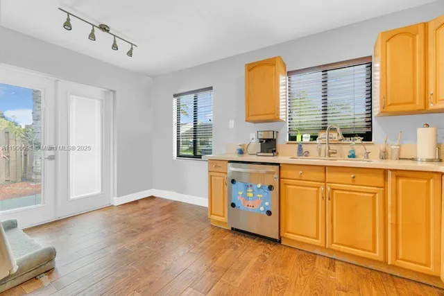 a kitchen with stainless steel appliances granite countertop a sink a stove cabinets and wooden floor