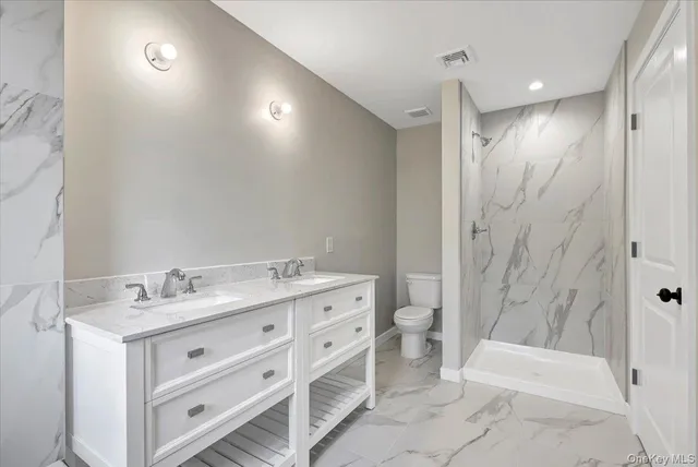 a bathroom with a double vanity sink toilet and shower
