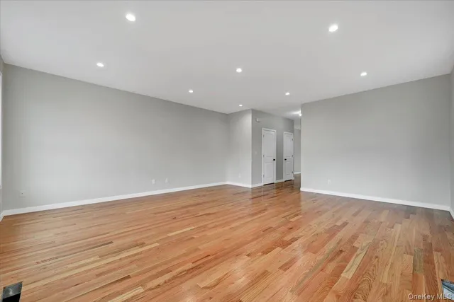 a view of an empty room with wooden floor and closet