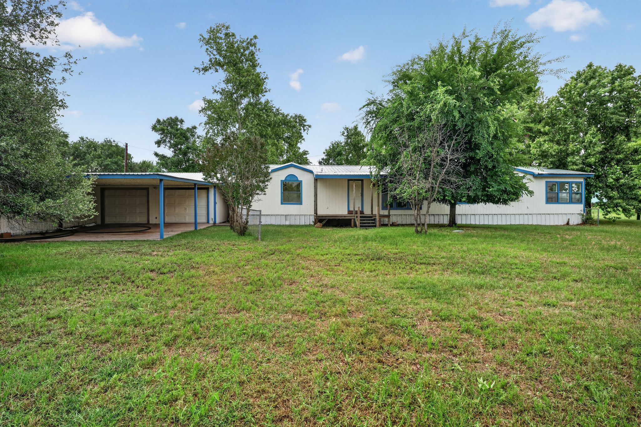 1192 County Road 225 Bluffton, TX 78607 - Photo 35 of 38 Expansive front yard featuring a white exterior structure with blue trim accents and a covered carport