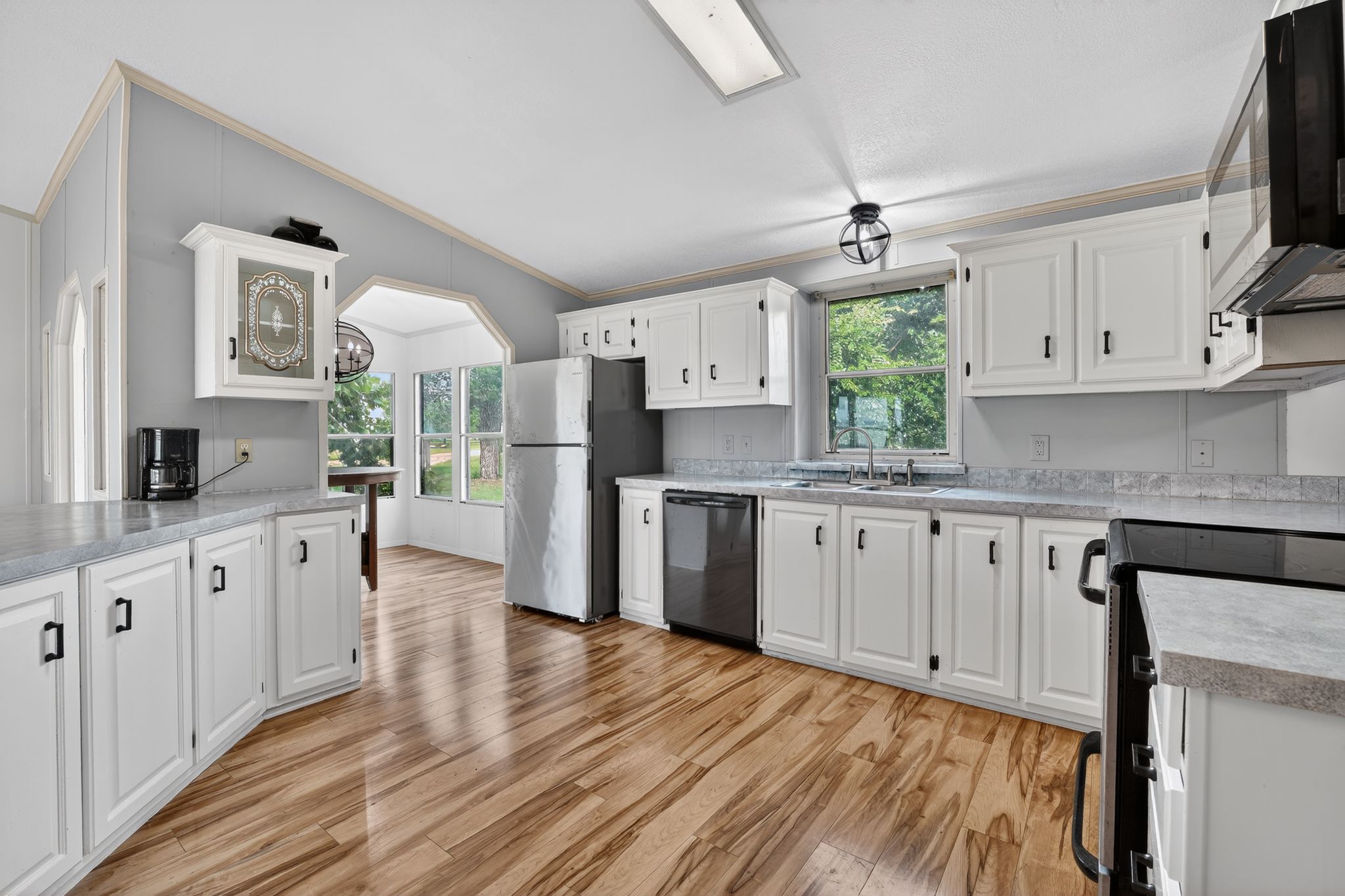 1192 County Road 225 Bluffton, TX 78607 - Photo 6 of 38 Kitchen featuring wood-finish flooring, white cabinetry with black hardware, stone-finish countertops, and stainless steel appliances