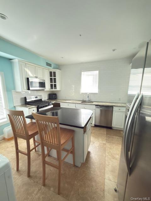 48 Church Street Patchogue, NY 11772 - Photo 11 of 19 a kitchen with stainless steel appliances granite countertop a sink a stove a dining table and chairs