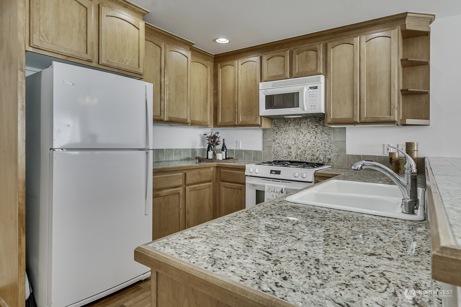 3121 West Government Way, Unit 405 Seattle, WA 98199 - Photo 9 of 29 a kitchen with stainless steel appliances granite countertop a refrigerator sink stove and microwave