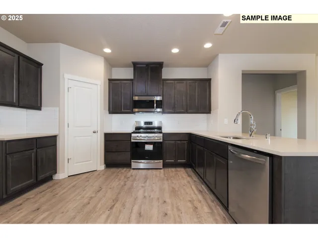 a kitchen with stainless steel appliances granite countertop a refrigerator a sink dishwasher and a oven with wooden cabinets