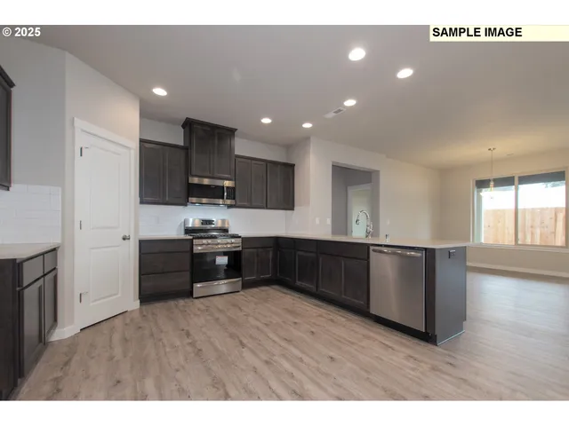 a kitchen with stainless steel appliances kitchen island granite countertop a stove a sink and a refrigerator with wooden floor