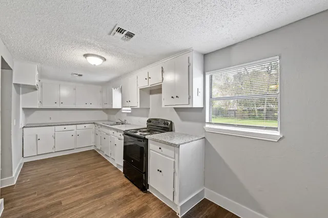 a kitchen with white cabinets appliances and a window