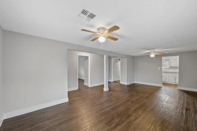 an empty room with wooden floor and ceiling fan