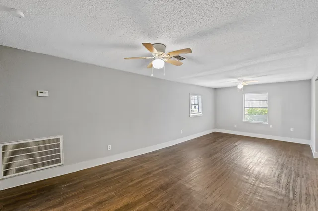 a view of an empty room with a window and wooden floor