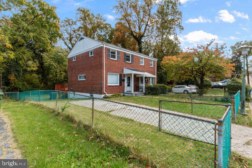 a view of house with a yard and a large tree