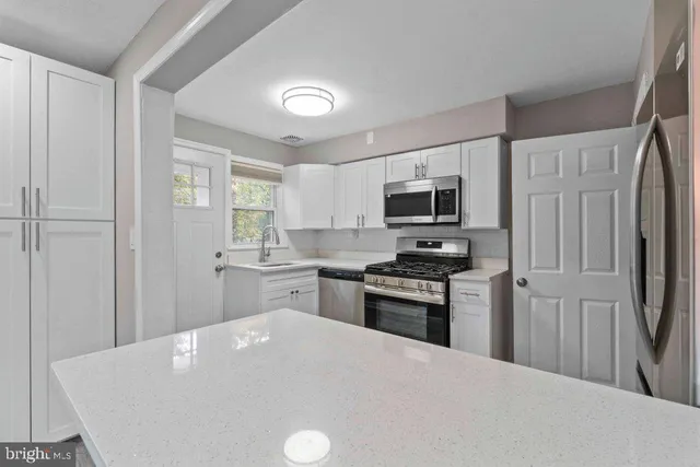 a kitchen with granite countertop a refrigerator stove top oven and sink