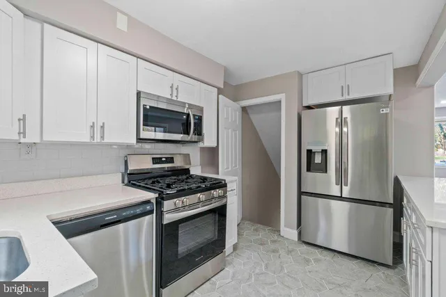 a kitchen with stainless steel appliances white cabinets and a stove top oven