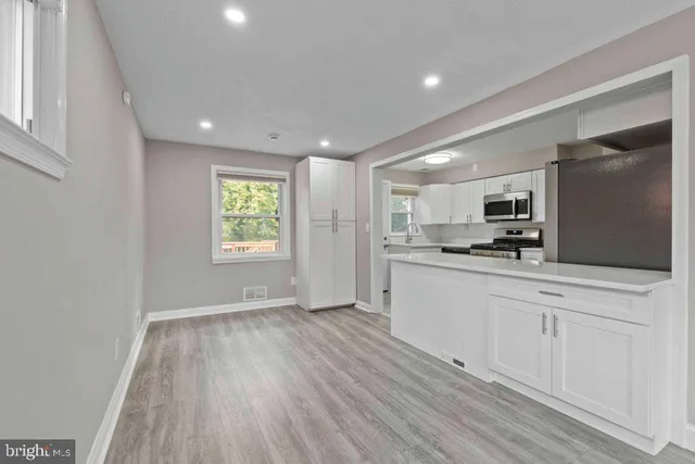 a large white kitchen with cabinets wooden floor and a window