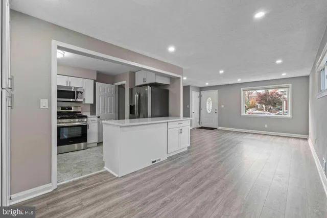 a view of a kitchen with wooden floor electronic appliances and hallway