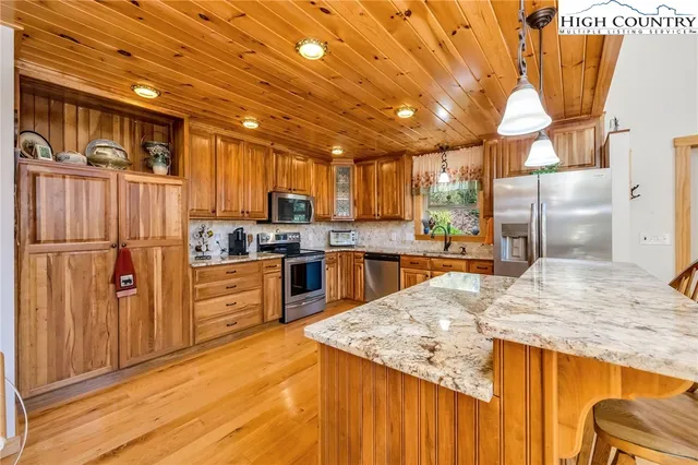 a dining room with stainless steel appliances kitchen island granite countertop a refrigerator a stove and a sink with granite countertops