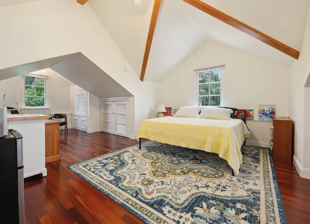 a bed sitting in a bedroom next to a window with wooden floor