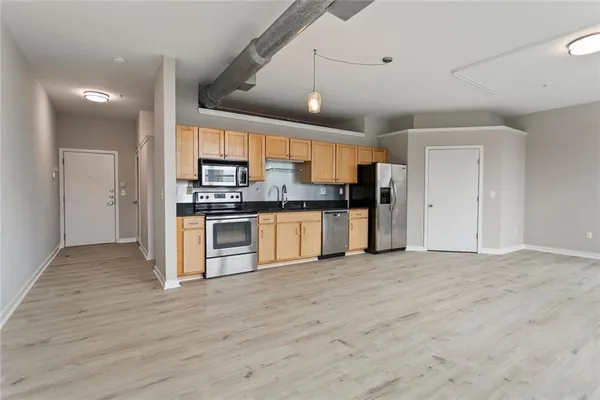 a view of kitchen with stainless steel appliances granite countertop a stove top oven a sink and a refrigerator