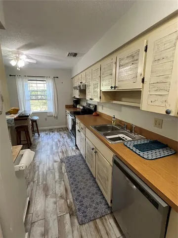 a kitchen with a stove a sink a window and cabinets
