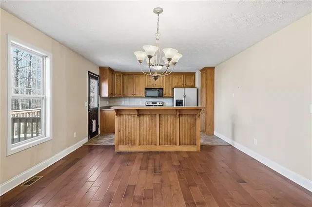 a view of a kitchen with granite countertop wooden floor a sink stainless steel appliances and cabinets