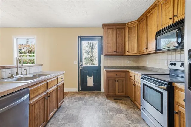 a kitchen with stainless steel appliances granite countertop a stove a sink and a microwave