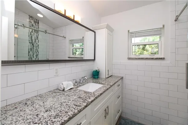 a bathroom with a granite countertop sink and a mirror