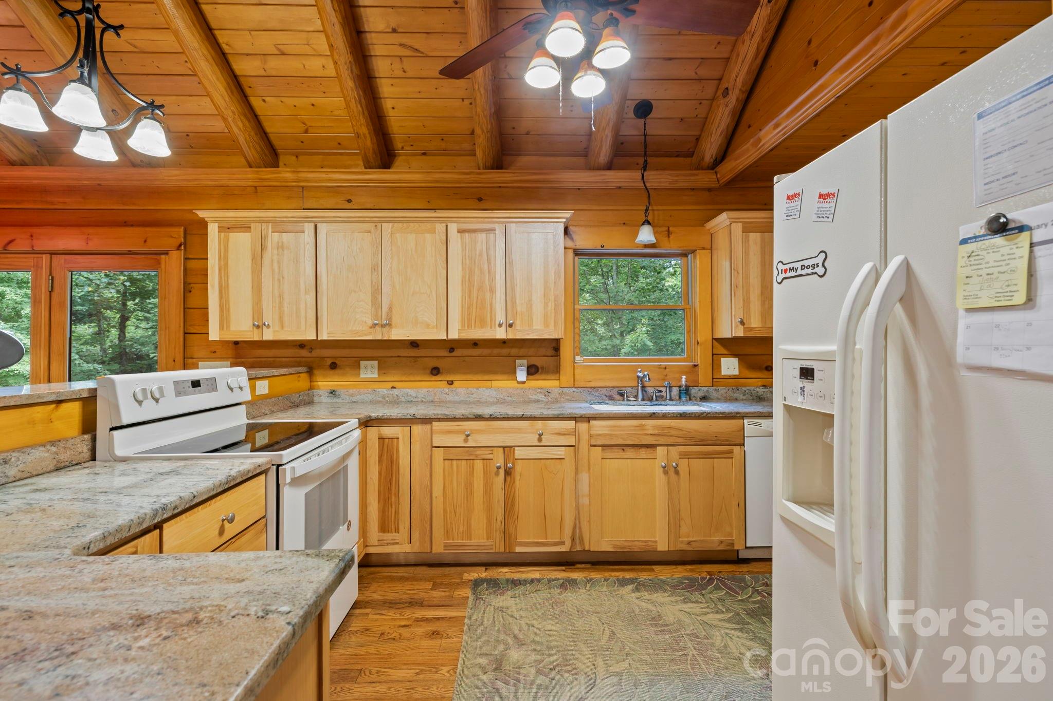 266 Rhododendron Drive Saluda, NC 28773 - Photo 11 of 35 a kitchen with stainless steel appliances granite countertop a refrigerator a sink dishwasher a stove a dining table and chairs with wooden floor