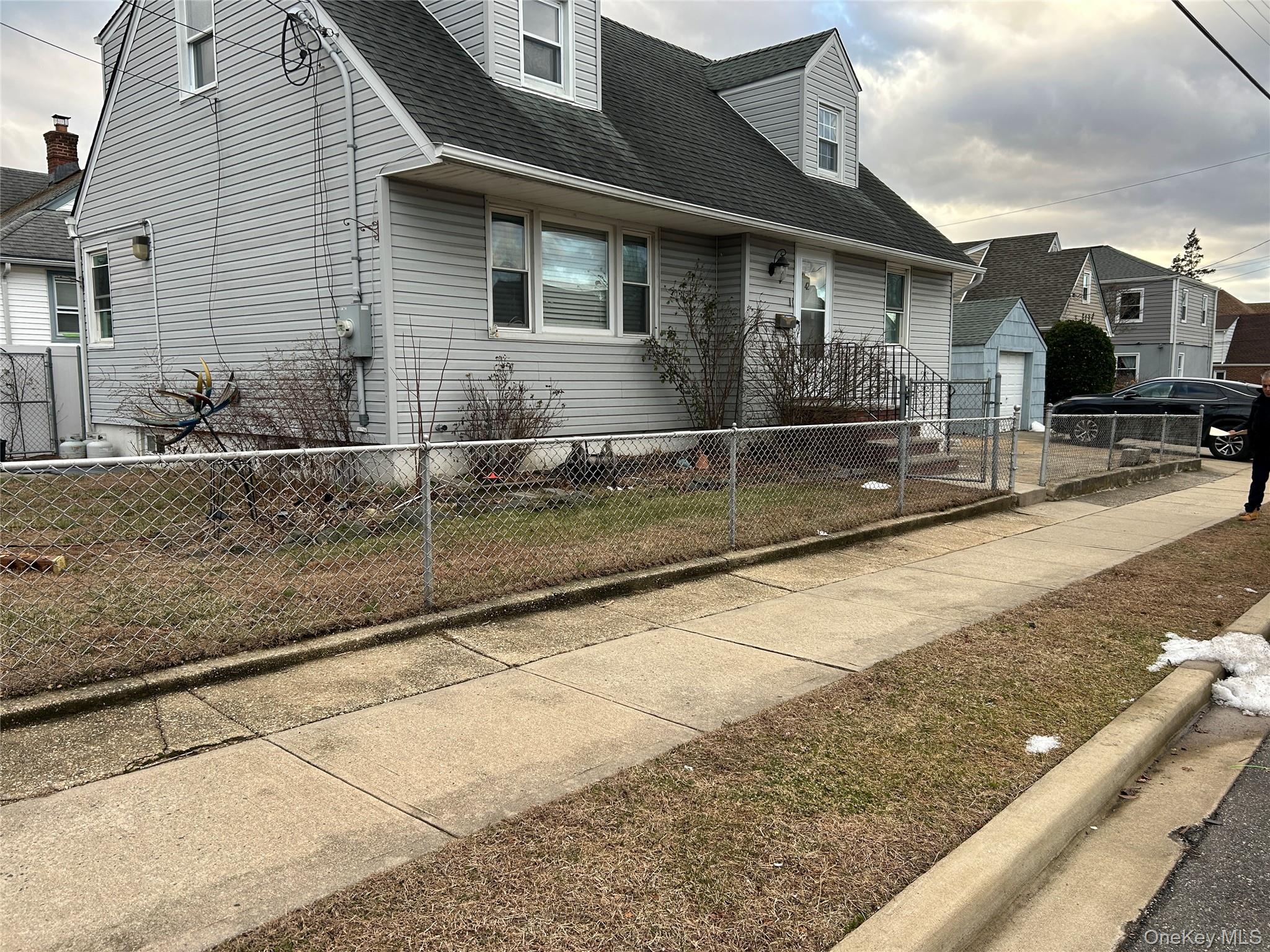 Cape cod home with a shingled roof and a fenced front yard