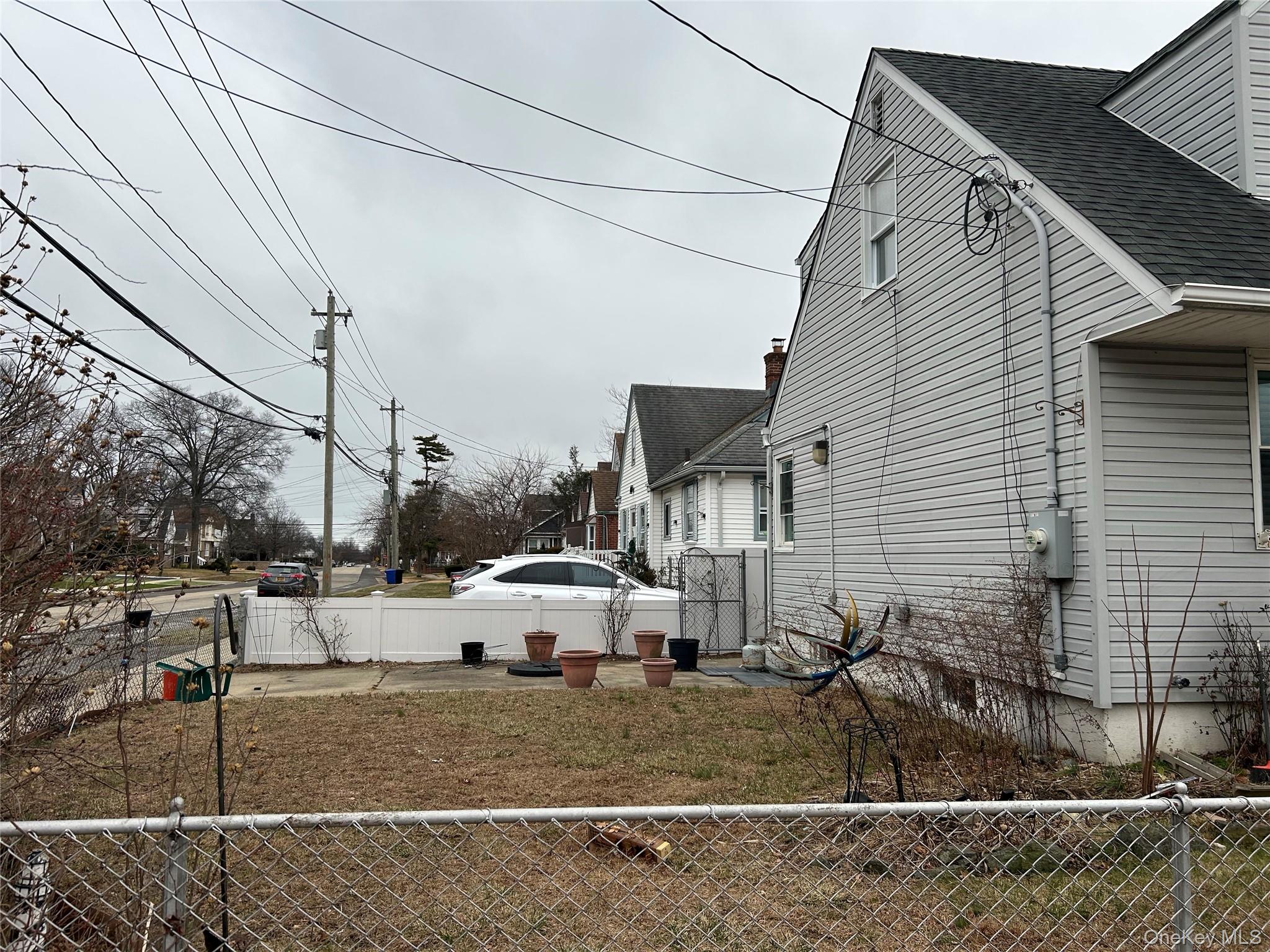 42 Princeton Street Valley Stream, NY 11580 - Photo 2 of 13 View of side of property featuring a fenced backyard, roof with shingles, and a patio