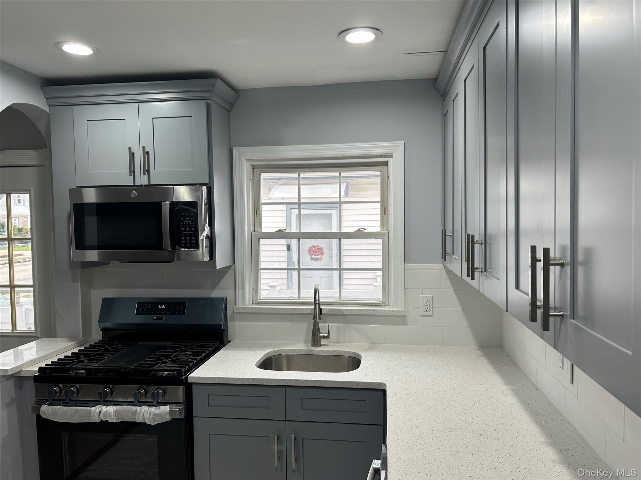 42 Princeton Street Valley Stream, NY 11580 - Photo 8 of 13 Kitchen featuring gray cabinetry, range with gas stovetop, light stone counters, and stainless steel microwave