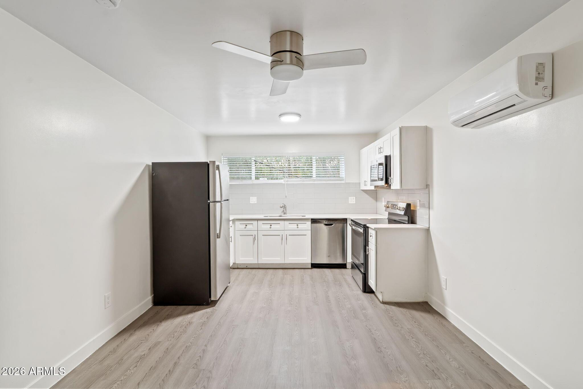 1707 North 18th Street, Unit B7 Phoenix, AZ 85006 - Photo 7 of 14 a kitchen with stainless steel appliances a refrigerator sink and white cabinets