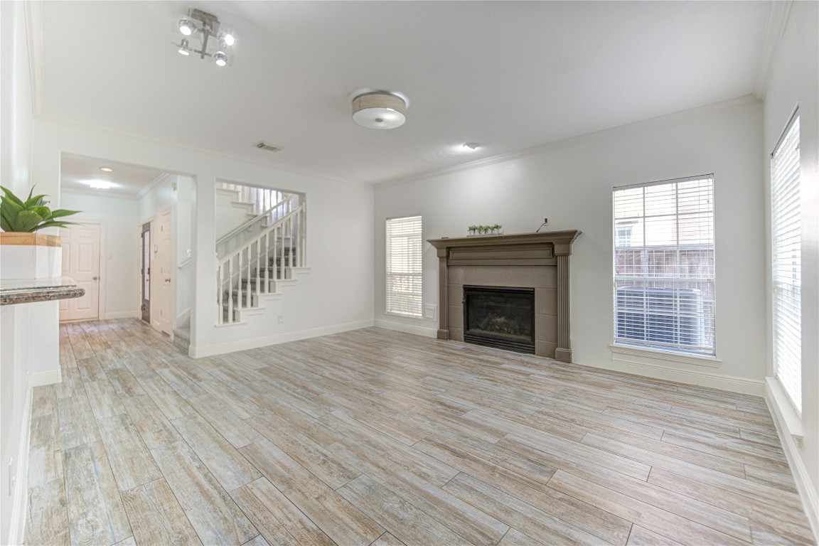 1115 Enclave Square East Houston, TX 77077 - Photo 13 of 42 Spacious and inviting living room with an open-concept layout and abundant natural light. The room features beautiful wood-look flooring that adds warmth and durability, complemented by soft neutral walls that create a bright, airy atmosphere.