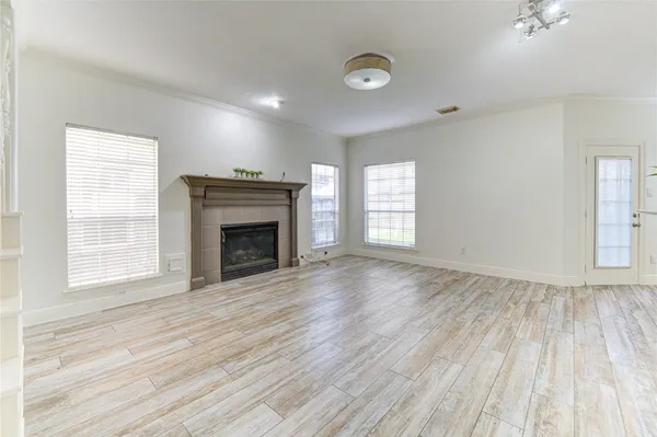 an empty room with wooden floor a fireplace and windows