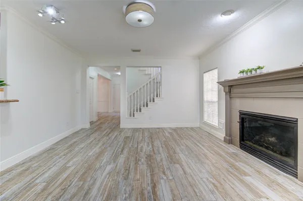 an empty room with wooden floor a fireplace and windows