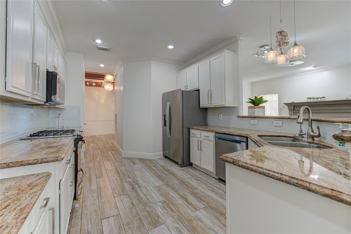 1115 Enclave Square East Houston, TX 77077 - Photo 5 of 42 Bright and modern kitchen featuring an open-concept design with elegant finishes. The space offers white shaker-style cabinetry, sleek stainless steel appliances, and beautiful granite countertops with subtle veining.