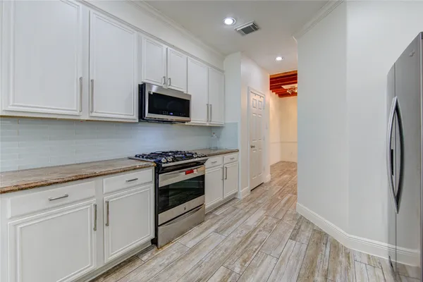 a kitchen with white cabinets stainless steel appliances and wooden floor