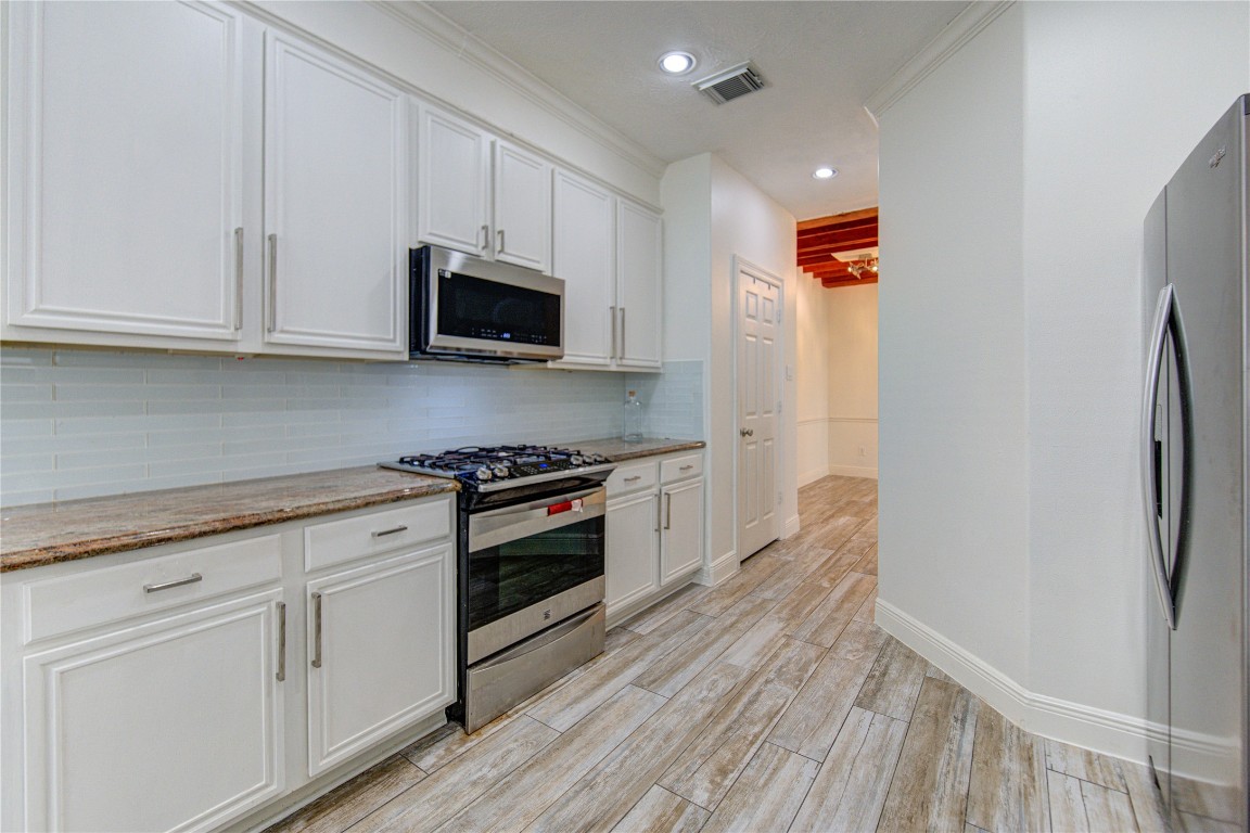 1115 Enclave Square East Houston, TX 77077 - Photo 6 of 42 Beautifully updated kitchen with a clean, modern design and bright, open feel. The space features crisp white cabinetry with sleek hardware, granite countertops, and a stylish tile backsplash that adds subtle texture.