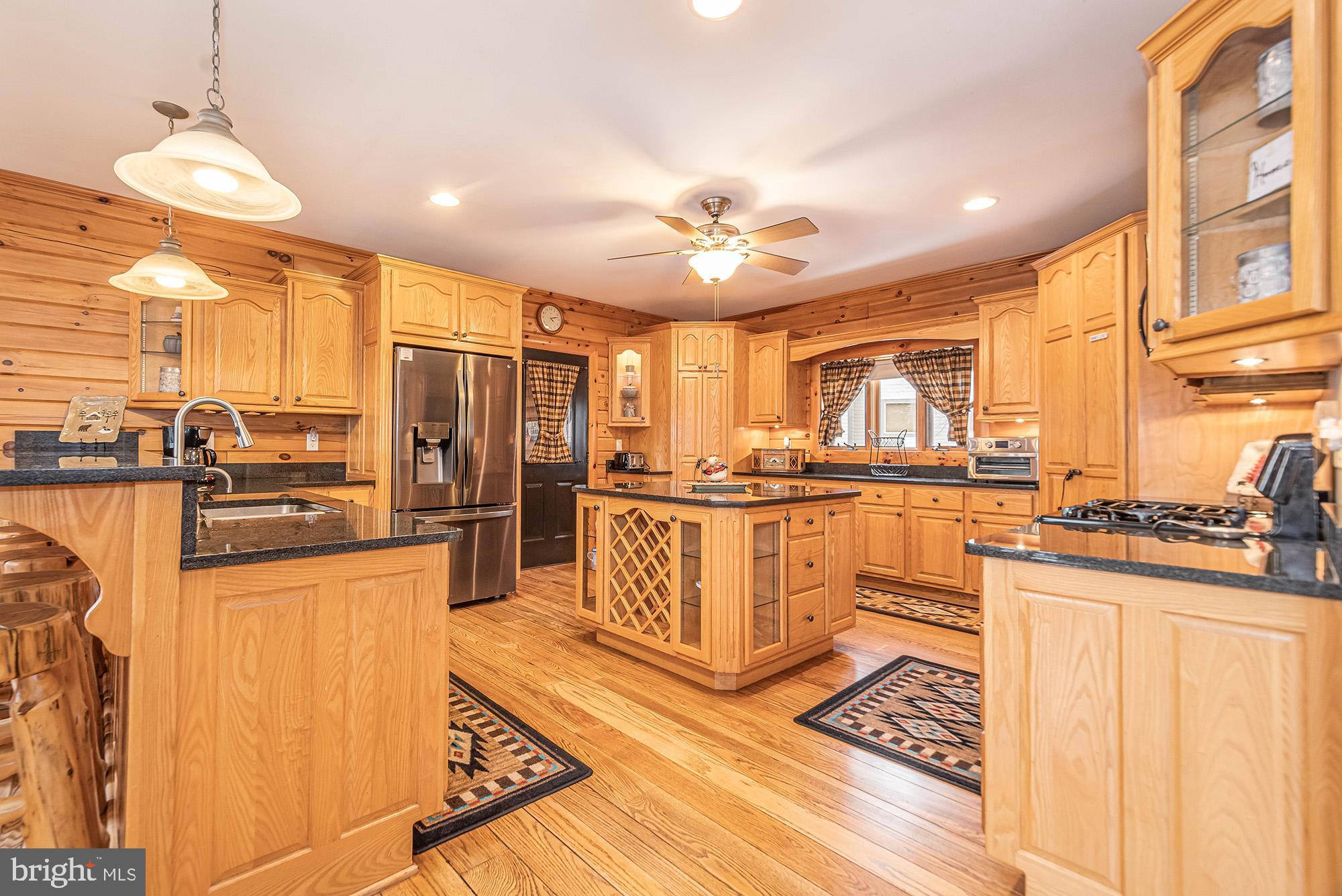 642 Deep Creek Highlands Road McHenry, MD 21541 - Photo 19 of 59 a kitchen with stainless steel appliances granite countertop a refrigerator a stove and a sink with wooden floor