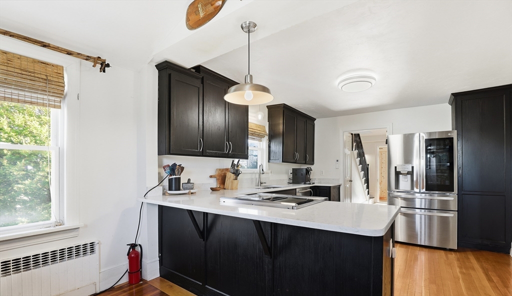 23 A Street Hull, MA 02045 - Photo 12 of 42 a kitchen with stainless steel appliances kitchen island granite countertop a sink and wooden floor