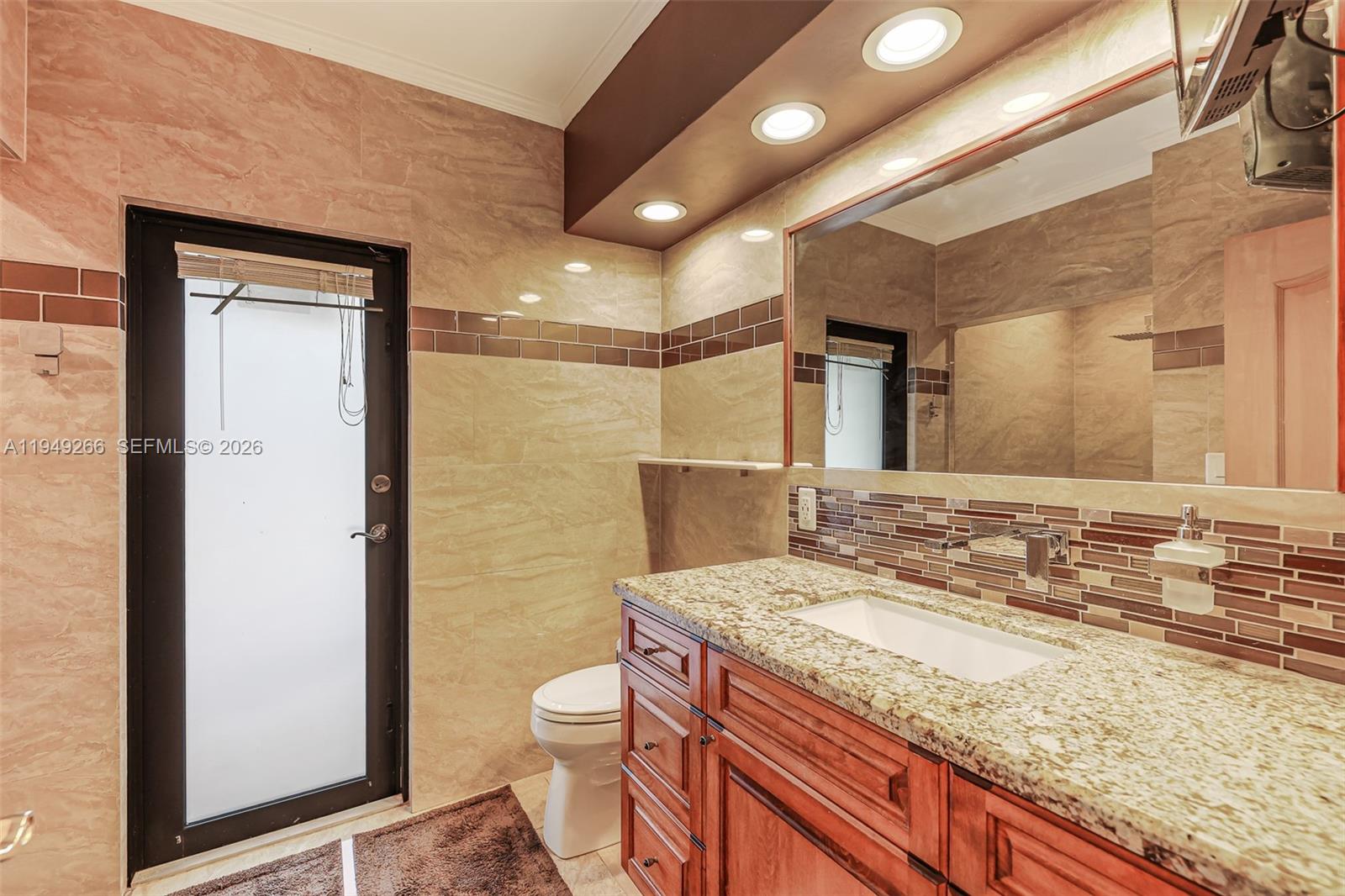 18975 Southwest 224th Street Miami, FL 33170 - Photo 38 of 97 a bathroom with a granite countertop sink a toilet a mirror and shower