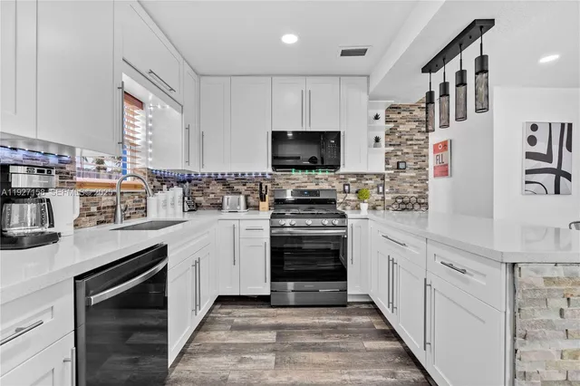 a kitchen with stainless steel appliances granite countertop a stove a sink and a refrigerator