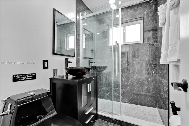 a bathroom with a granite countertop sink a mirror and a shower