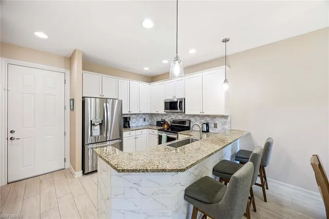 a kitchen with stainless steel appliances granite countertop a refrigerator a stove a sink dishwasher a dining table and chairs with wooden floor