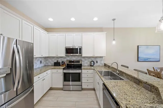 a kitchen with stainless steel appliances granite countertop a sink stove microwave and refrigerator