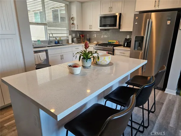 a kitchen with stainless steel appliances a dining table chairs refrigerator and sink