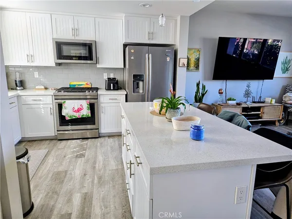 a kitchen with stainless steel appliances a stove a microwave a sink a refrigerator and white cabinets