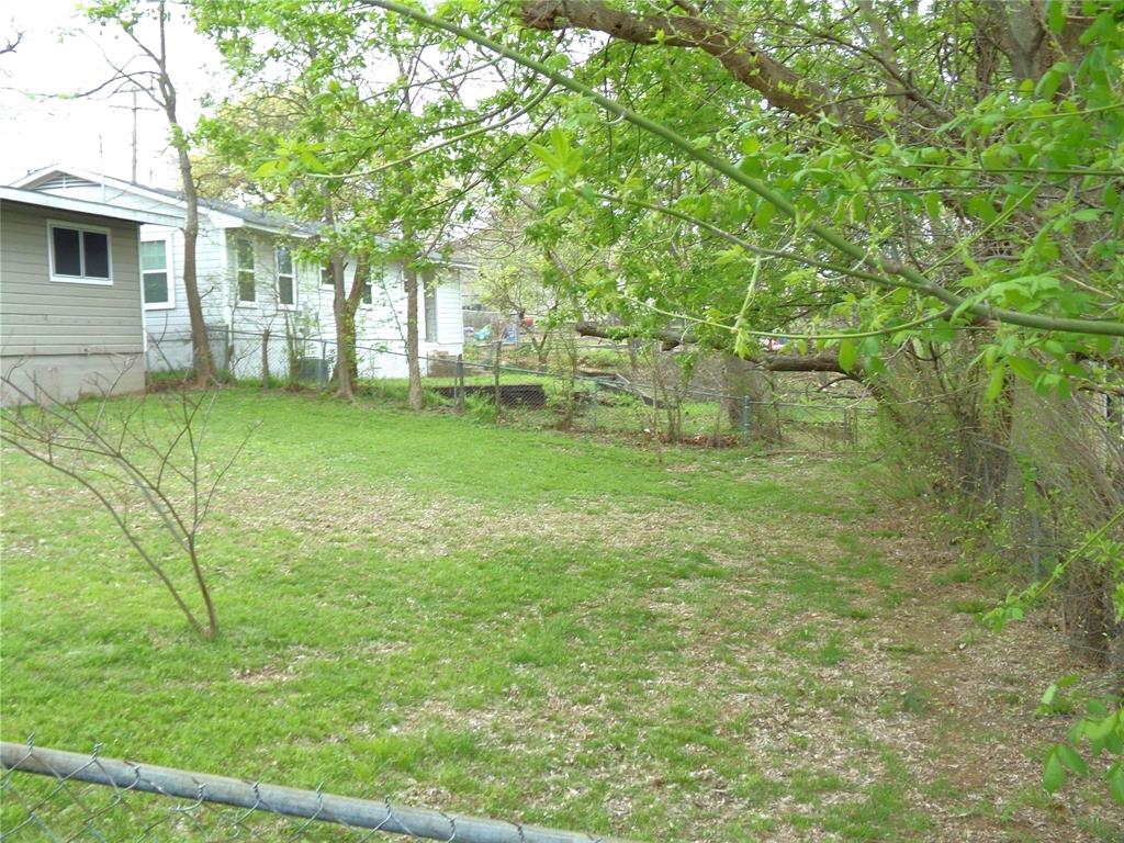 501 South Perry Avenue Denison, TX 75020 - Photo 11 of 11 Expansive grassy yard with mature trees and a chain-link fence
