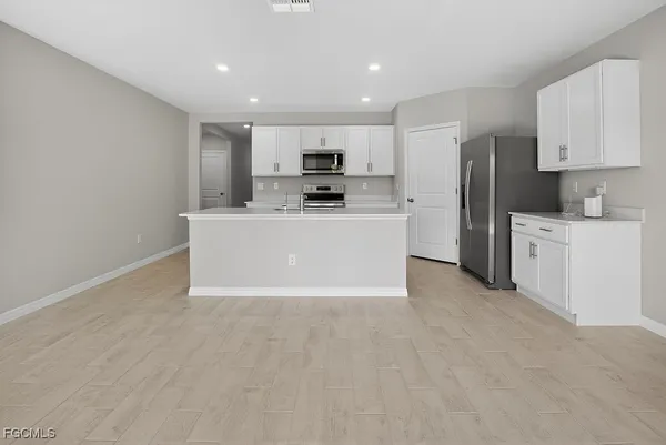 a view of kitchen with stainless steel appliances a refrigerator a stove top oven a sink and cabinets