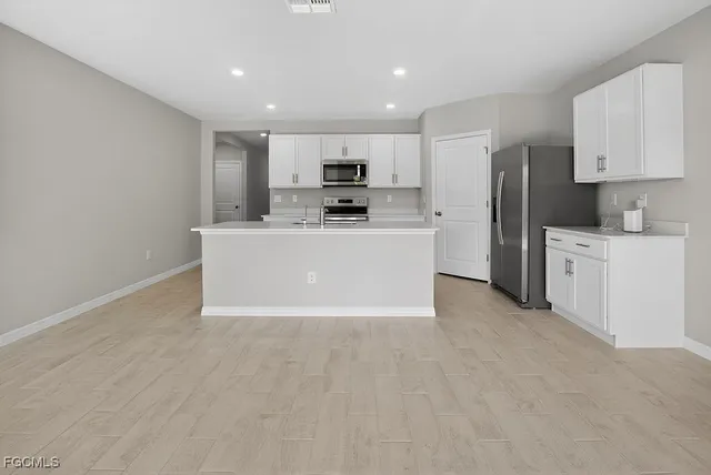 a view of kitchen with stainless steel appliances a refrigerator a stove top oven a sink and cabinets