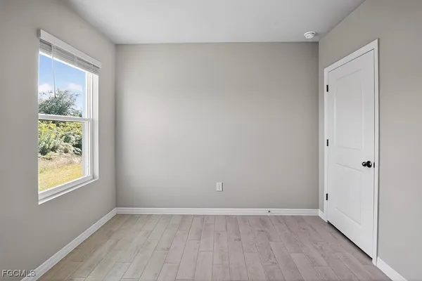 a view of an empty room with window and wooden floor